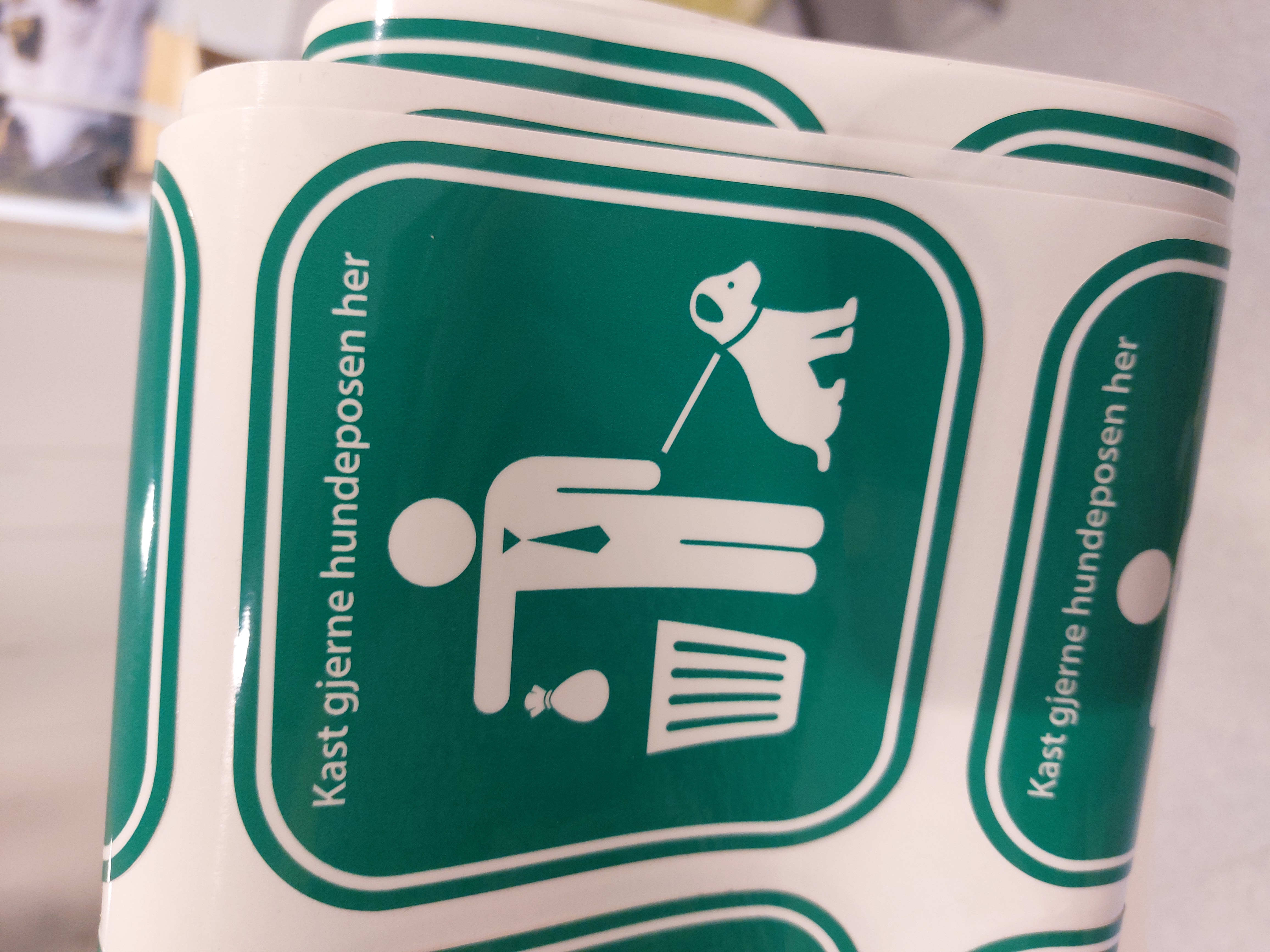 klistermerke til restavfallsdunken med teksten Kast gjerne hundeposen her. Foto